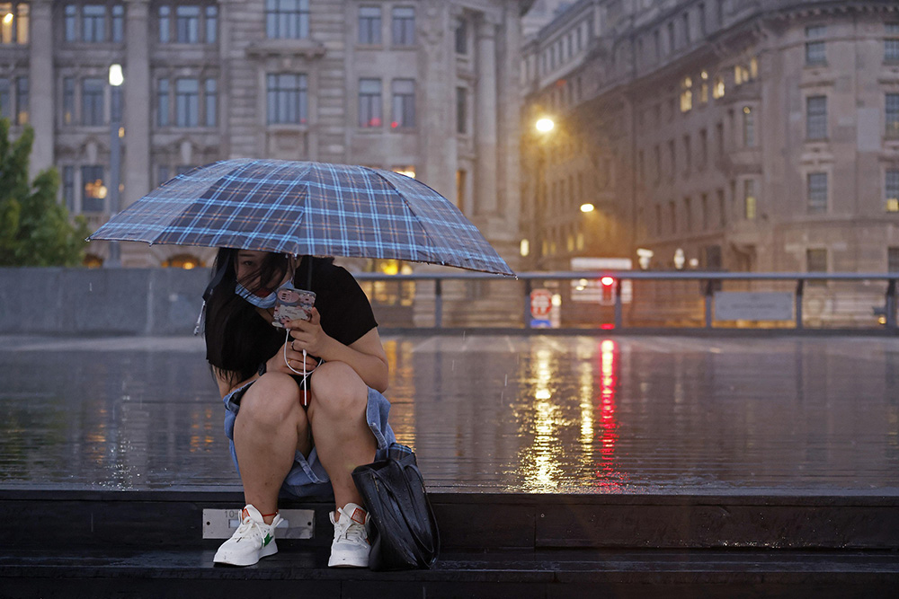 2022年9月4日，上海，游客冒雨在外滩滨江步道上短暂停留。 中新社记者 殷立勤 摄